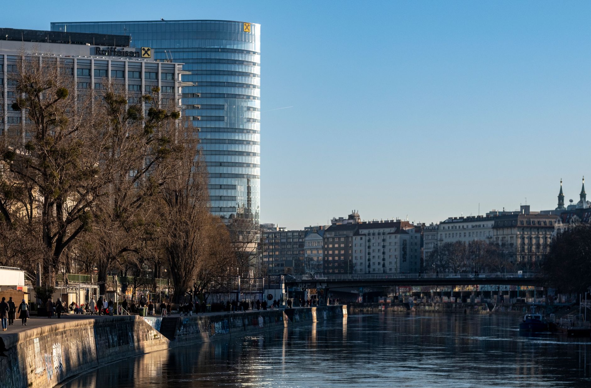 Urban landscape featuring artistic graffiti and modern architecture along the Danube Canal in Vienna.