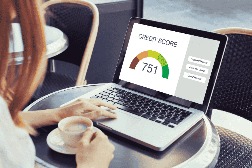 Person checking a 751 credit score on a laptop screen at a café.