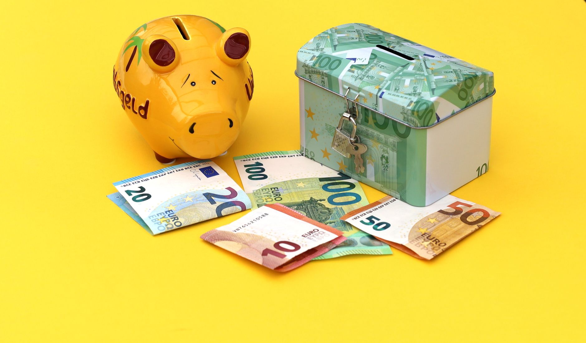 Yellow piggy bank and cash box with Euro notes on bright background.