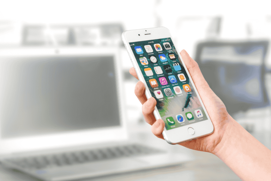 Hand holding a smartphone with various app icons used for personal finance management.