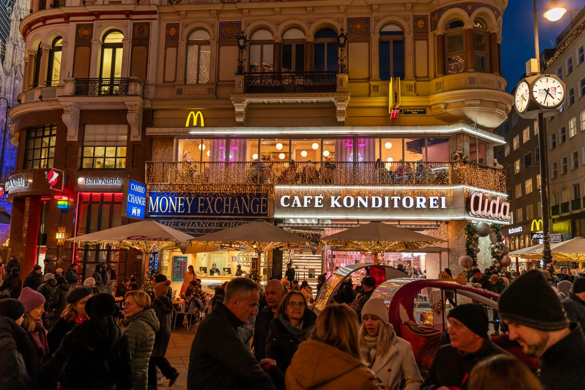 Lively street scene in Vienna featuring Café Konditorei and festive lights.