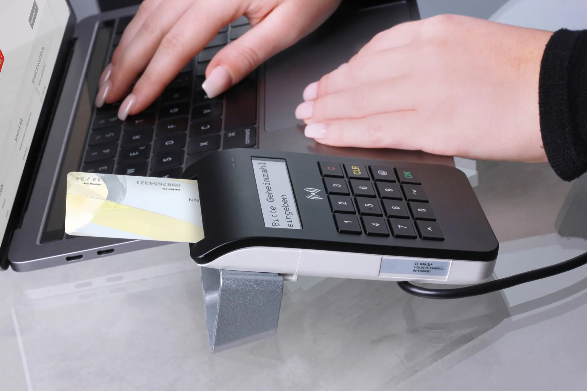 Close-up of contactless payment using laptop and card reader, showcasing modern office technology.