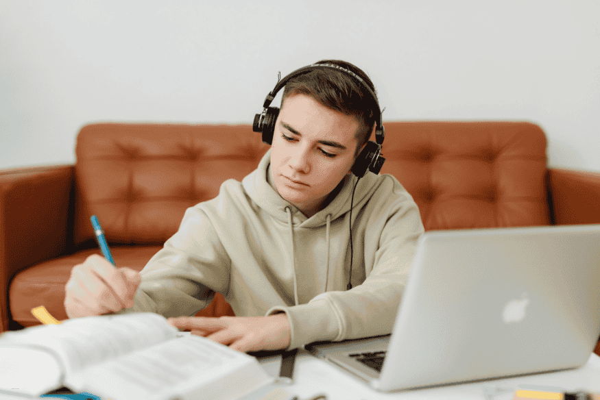 College student studying with laptop and notebook while researching student credit cards before applying