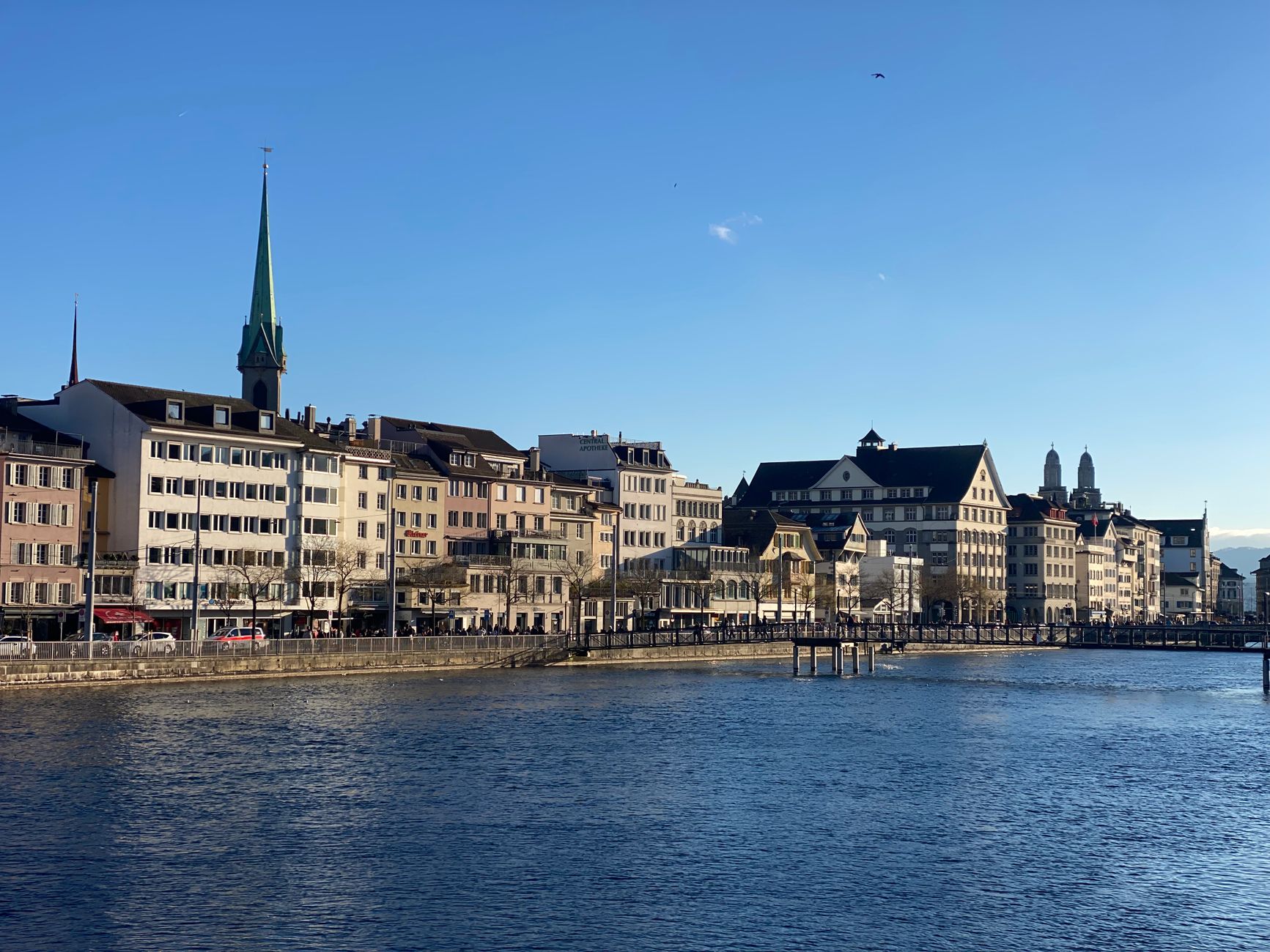 Beautiful sunny day in Zürich with historic buildings and clear water reflecting cityscape charm.