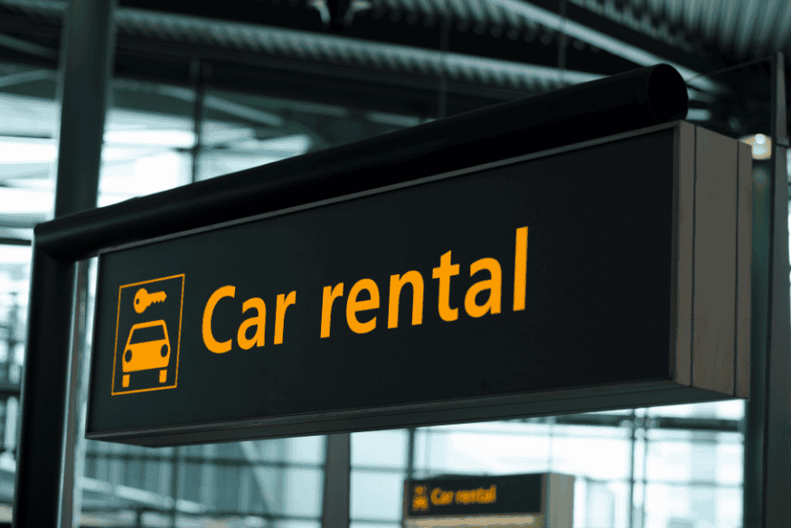 Placa eletrônica indicando área de aluguel de carros no aeroporto