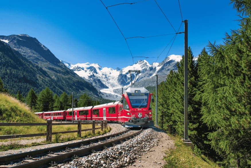Trem vermelho atravessando paisagem alpina com montanhas nevadas ao fundo
