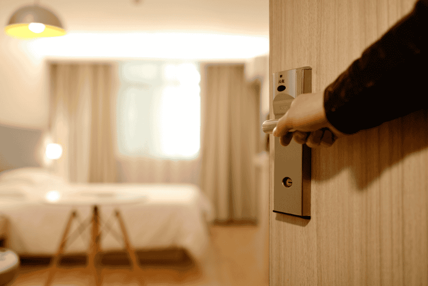 Pessoa abrindo porta de quarto de hotel com cartão magnético.
