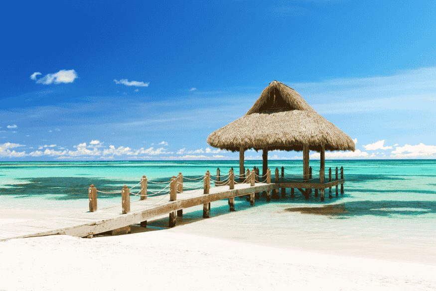 Gazebo com palha sobre o mar azul-turquesa em praia paradisíaca de Punta Cana
