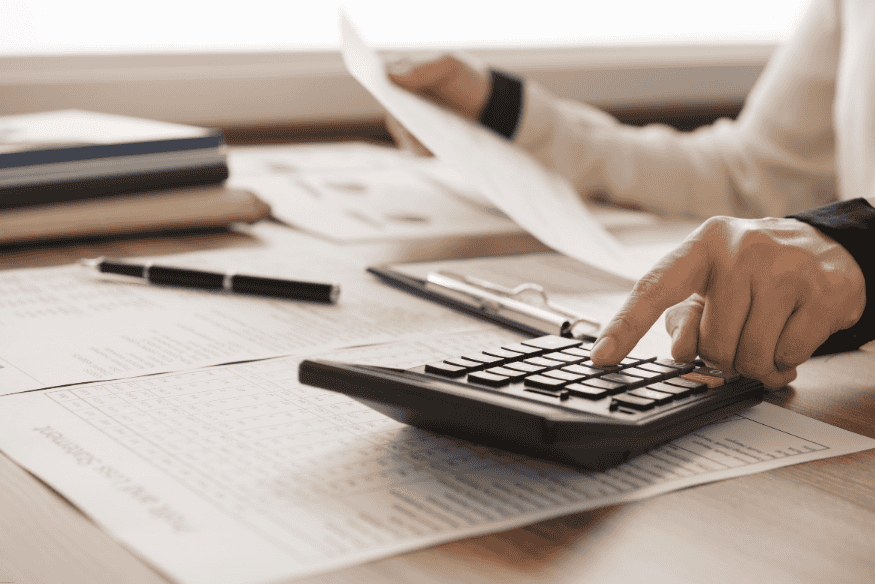 Pessoa usando calculadora para revisar documentos financeiros.