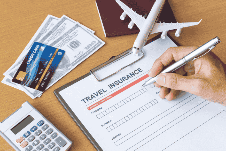 Formulário de seguro-viagem sendo preenchido ao lado de passaporte, cartões e dinheiro