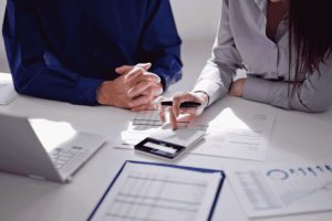 Two professionals reviewing financial reports and calculator to decide between cash and accrual accounting