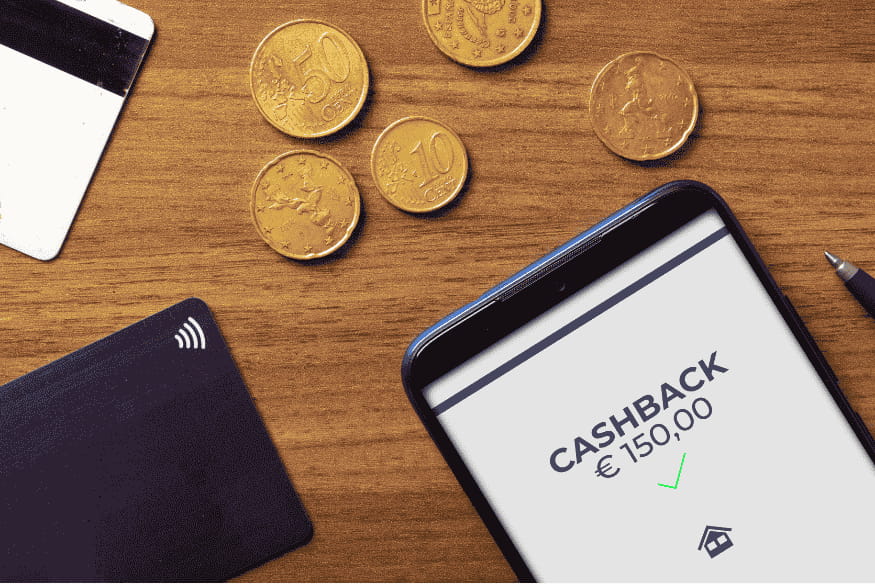 Smartphone showing €150 cashback confirmation beside credit cards and euro coins on a wooden table.