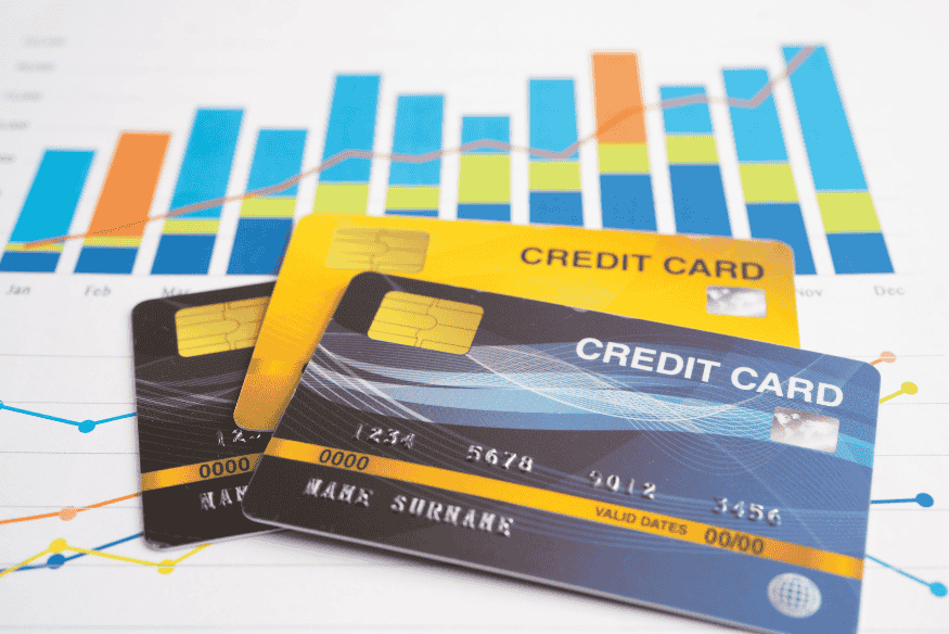 Multiple credit cards on top of a financial chart showing spending and rewards trends.