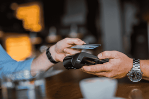 Person making a contactless payment with a credit card at a store terminal.