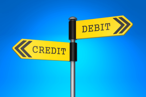 Yellow road signs pointing to credit and debit, symbolizing the decision between credit card and debit card.