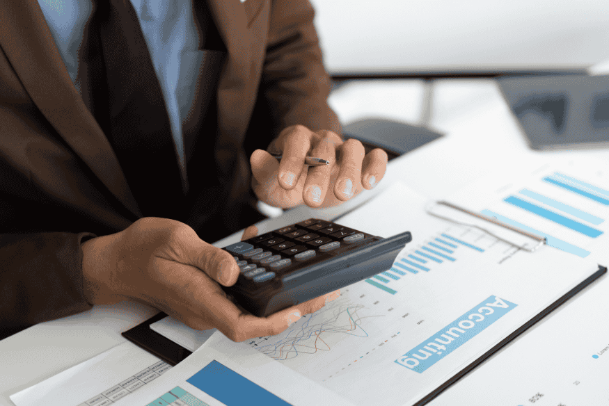 Professional reviewing accounting reports and using a calculator to analyze overall financial health