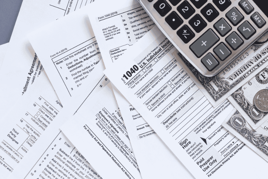 US tax forms with calculator and dollar bills representing freelance and self-employed tax paperwork