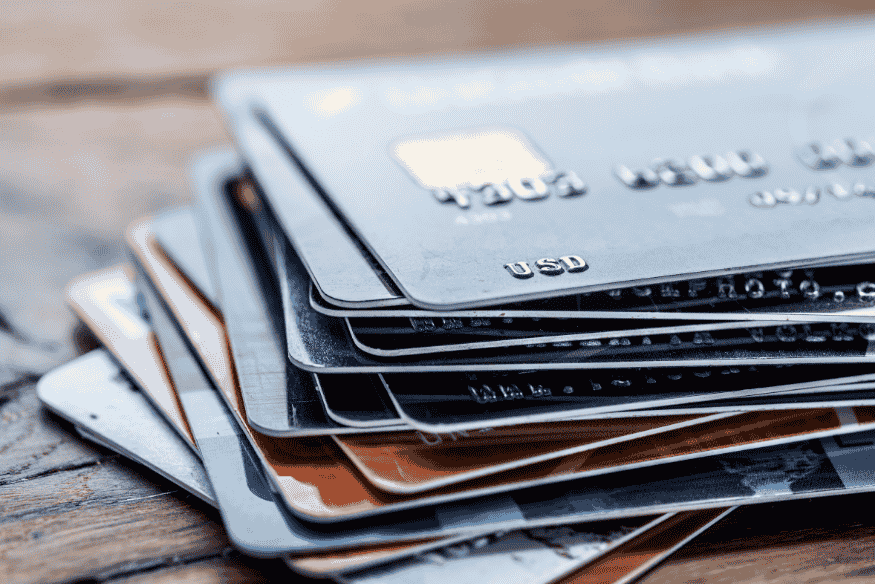 Stack of credit cards on a wooden table symbolizing high-interest debt and the need for a low-interest card.