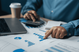 Person analyzing bar charts with calculator and laptop to plan a budget around irregular income