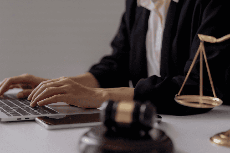 Person working at a laptop beside scales of justice, reviewing credit card terms and conditions to optimize rewards.