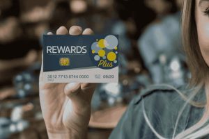 Woman holding a rewards credit card, symbolizing how to maximize points and cash back on every purchase.