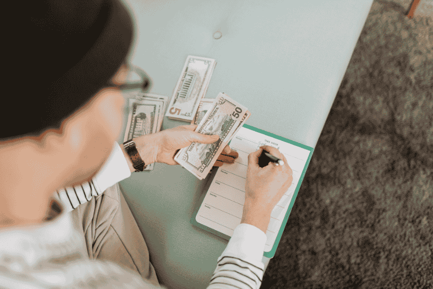 Man counting cash and writing in a weekly planner as part of personal financial planning for beginners