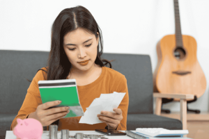 Young woman reviewing receipts and notes while organizing her personal financial plan at home