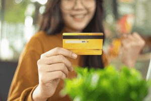 Young woman happily holding a yellow secured credit card after approval.