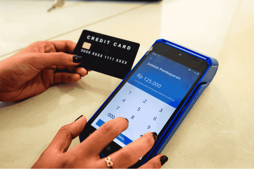 Customer using a secured credit card to pay at a card terminal for an everyday purchase.