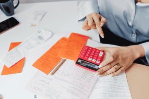 Person sorting bills and receipts with a calculator to organize personal and business finances