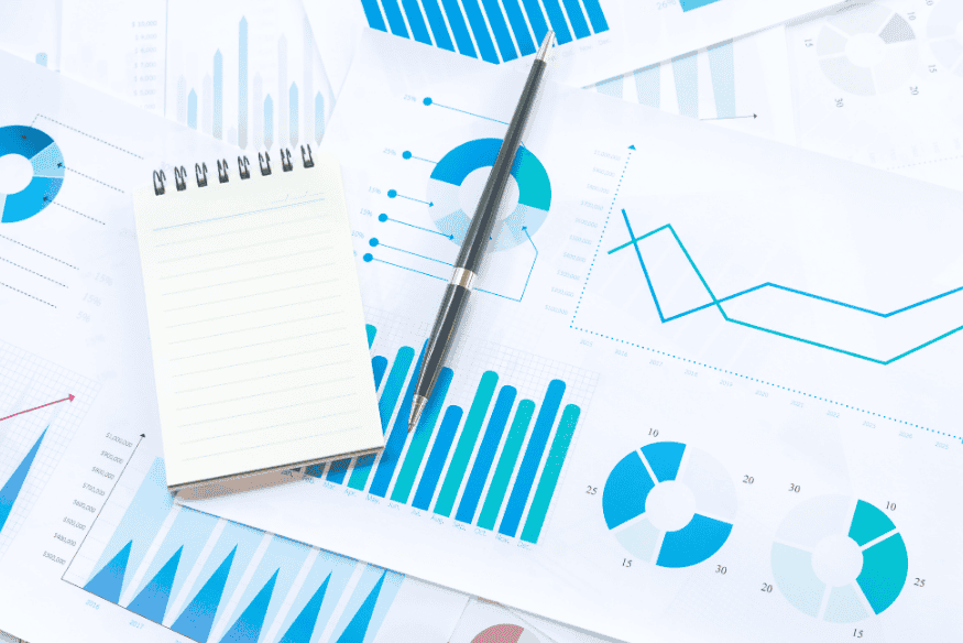 Notebook and pen on financial charts used to track separate budgets for personal and business money