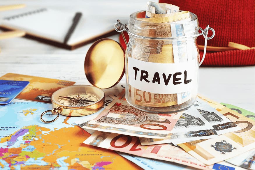 Glass jar labeled travel filled with cash on a map, representing a sinking fund for future vacations