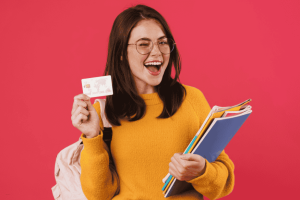 Excited student holding a new student credit card and school notebooks